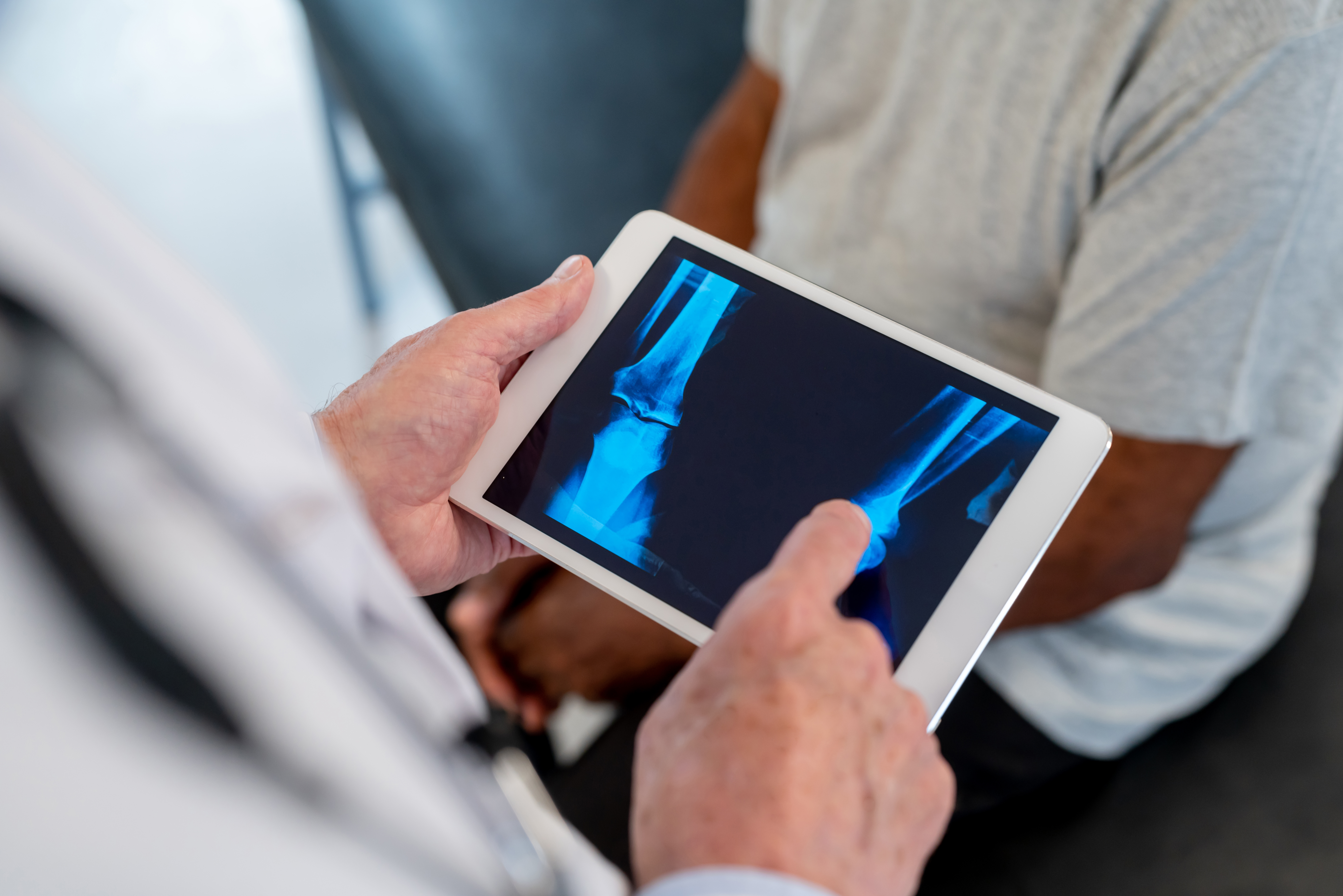 Orthopedic surgeon conducting a detailed consultation with a patient to assess hip or knee condition